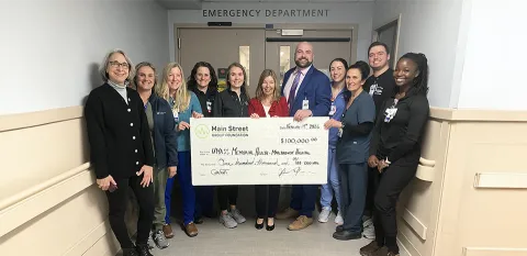 A group of caregivers at the Marlborough Campus hold up a large-size check.
